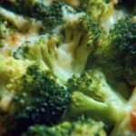Bowl of creamy cheesy broccoli garnished with herbs