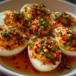 Spicy chili garlic deviled eggs on a platter, garnished with herbs