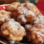 Freshly made cinnamon apple fritters dusted with powdered sugar.