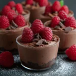 Raspberry chocolate mousse cups topped with fresh raspberries and chocolate shavings