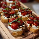 Delicious ricotta crostini topped with roasted tomatoes on a serving platter.