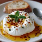 Simple burrata appetizer drizzled with honey on a rustic wooden board.