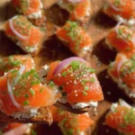 Plate of smoked salmon crostini topped with herbs and capers