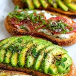 Healthy avocado toast topped with fresh ingredients on whole grain bread.