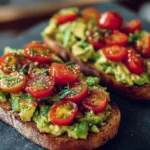 Avocado toast topped with fresh tomatoes on a rustic wooden table