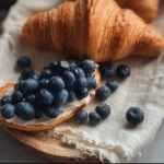 Croissant filled with fresh blueberries on a rustic wooden table