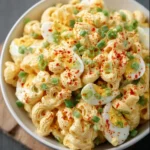 Bowl of deviled egg pasta salad garnished with herbs and spices
