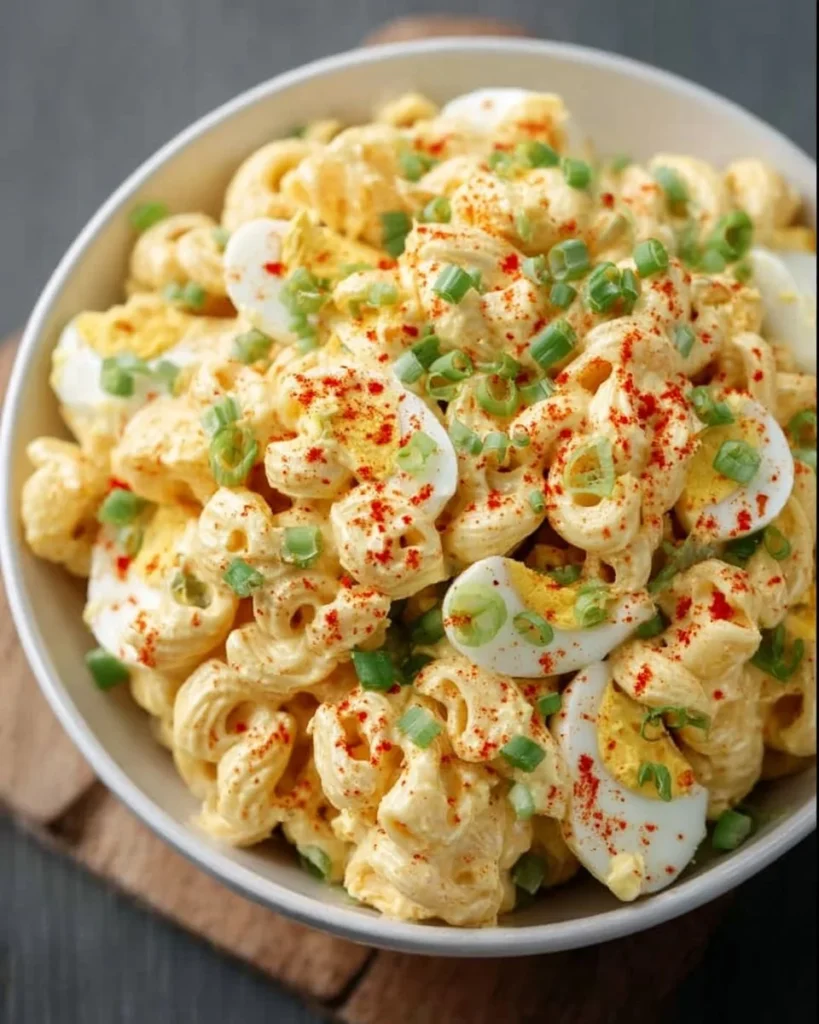 Bowl of deviled egg pasta salad garnished with herbs and spices