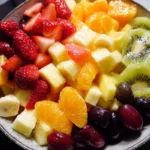 A bowl of easy fruit salad with a mix of fresh fruits like berries, melons, and bananas.