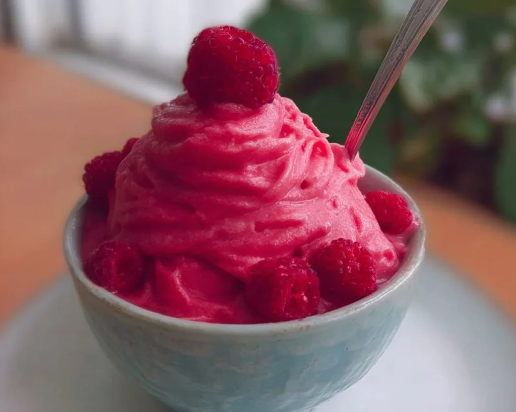 Delicious bowl of Raspberry Frozen Yogurt topped with fresh raspberries