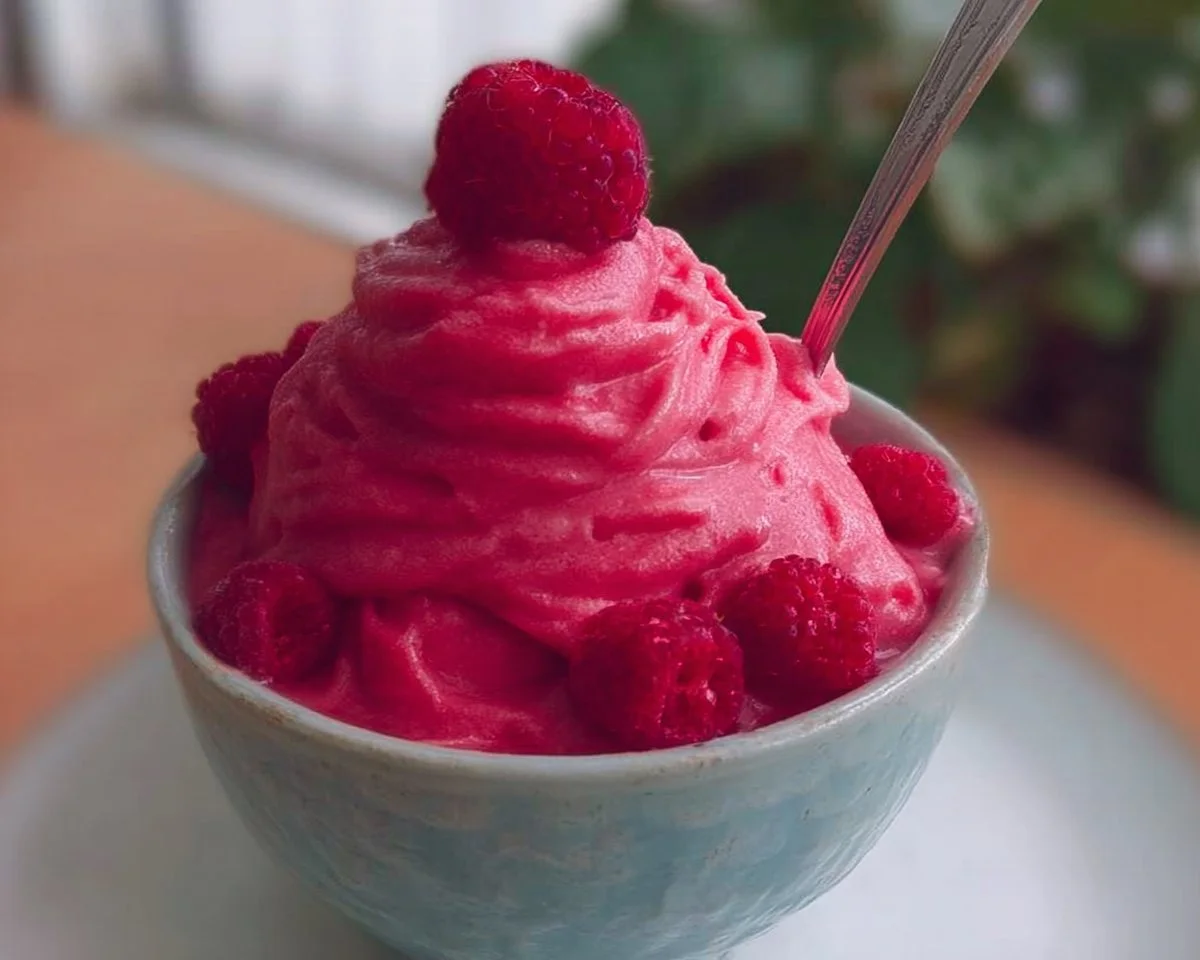 Delicious bowl of Raspberry Frozen Yogurt topped with fresh raspberries