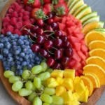 Colorful rainbow fruit platter with cherries, blueberries, and more healthy snacks