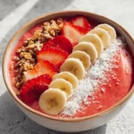 Strawberry banana smoothie bowl topped with fruits and granola