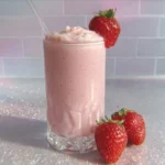 Homemade strawberry protein shake in a glass, garnished with fresh strawberries.