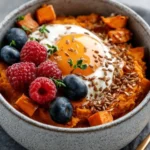 Delicious sweet potato breakfast bowl topped with nuts and berries