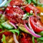 A colorful, fresh salad with various vegetables and dressing served in a bowl.
