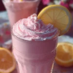 Refreshing whipped pink lemonade in a glass with a slice of lemon.