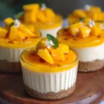 No bake mango cheesecake cups in a clear dessert cup with fresh mango slices