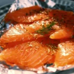 Delicious smoked salmon garnished with herbs and lemon slices.