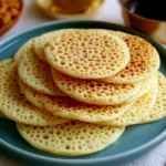 Baghrir Moroccan pancakes topped with honey and butter on a plate.