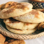Freshly baked Khobz, traditional Moroccan bread, on a wooden table.