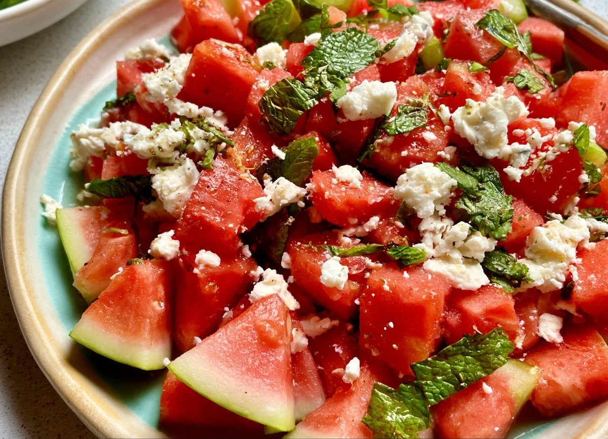 Fresh watermelon salad topped with crumbled feta cheese and mint leaves