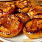 Grilled peaches served on a plate, showcasing their caramelized and juicy texture.