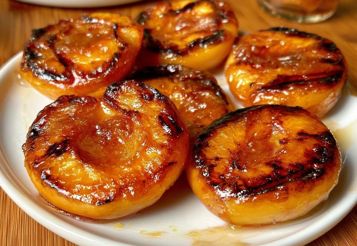 Grilled peaches served on a plate, showcasing their caramelized and juicy texture.