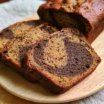 Sliced Hojicha Banana Bread topped with bananas and nuts on a wooden table