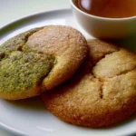 Freshly baked tea-infused sugar cookies on a plate with tea leaves