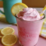 Whipped pink lemonade in a glass topped with whipped cream and lemon slices