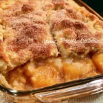Delicious double crust peach cobbler fresh out of the oven, golden and bubbly.
