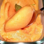 Bowl of easy homemade peach sorbet topped with fresh mint leaves